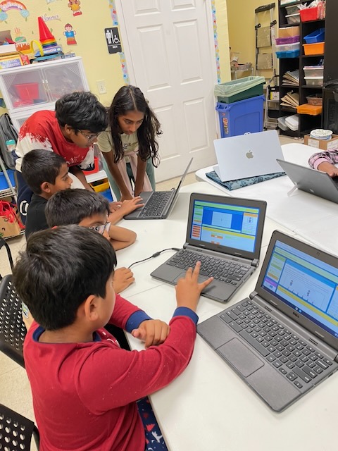 Children comparing their games and helping each other at a classroom table.