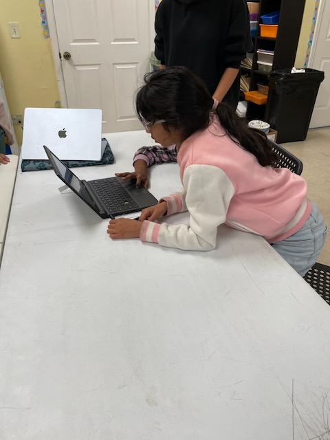 Students sharing a laptop as they work through their game.